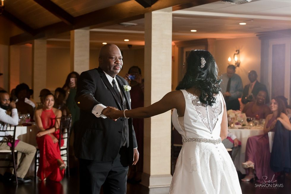 Bride and groom dancing at a reception with guests seated around them