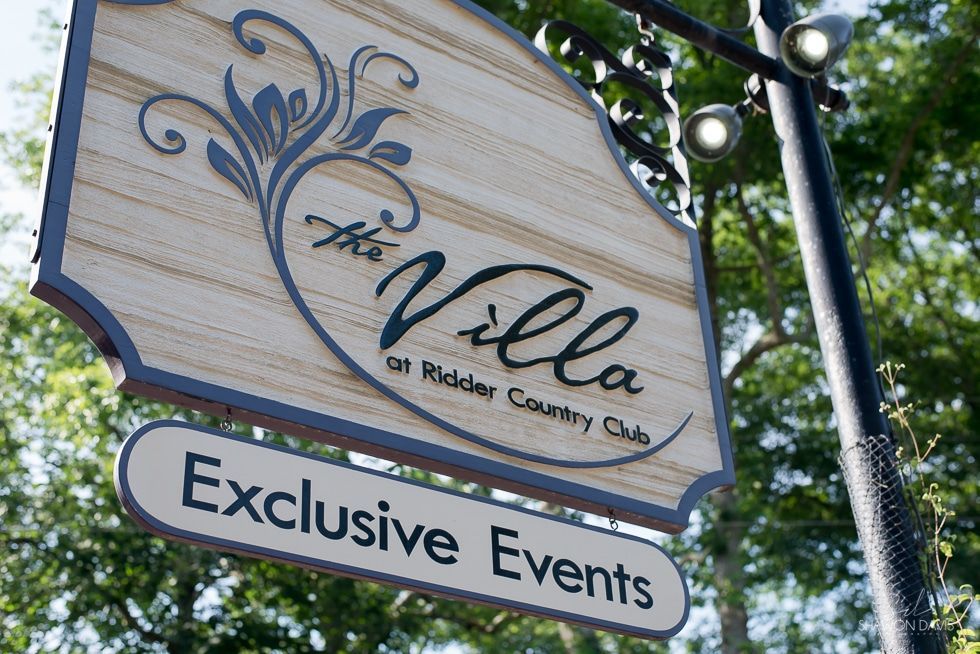 Wooden sign for LaVilla and an “Exclusive Events” placard hanging outdoors among trees