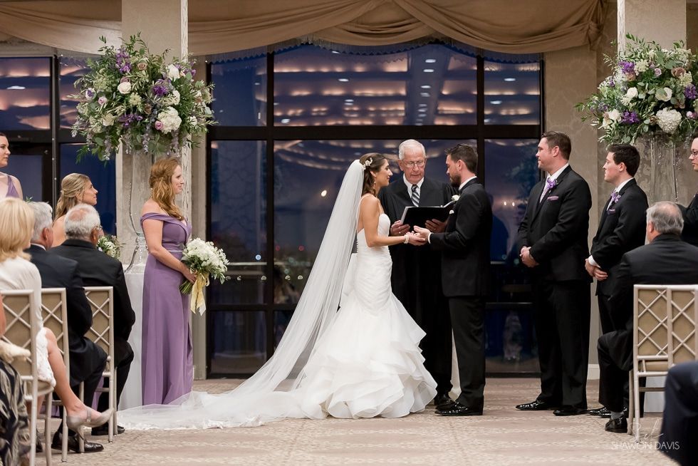 Wedding ceremony with bride and groom at altar, officiant, and guests in a decorated indoor venue