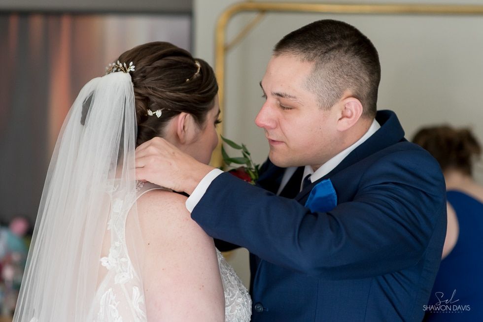 Bride and groom share an intimate moment during their wedding ceremony, with the groom adjusting her veil.