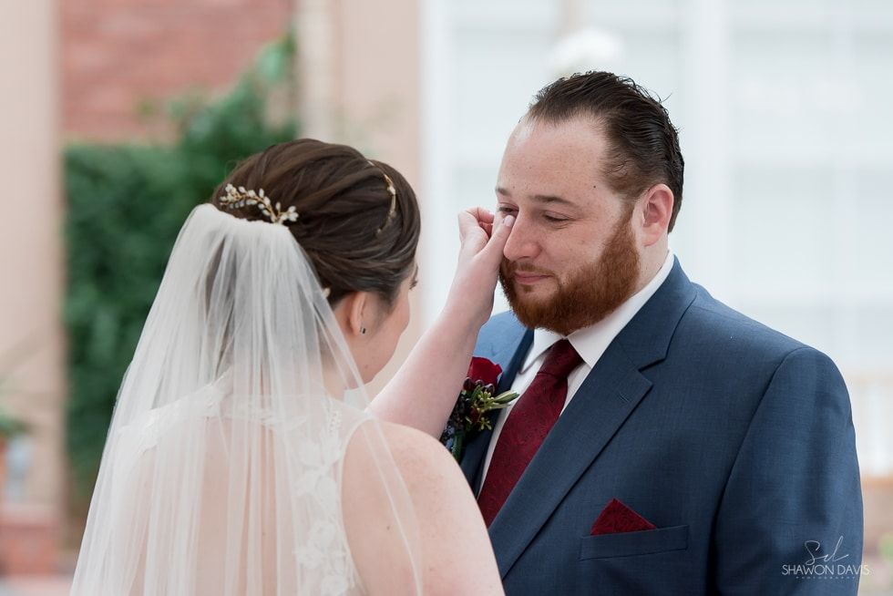 Bride gently wipes groom’s eye during outdoor wedding ceremony