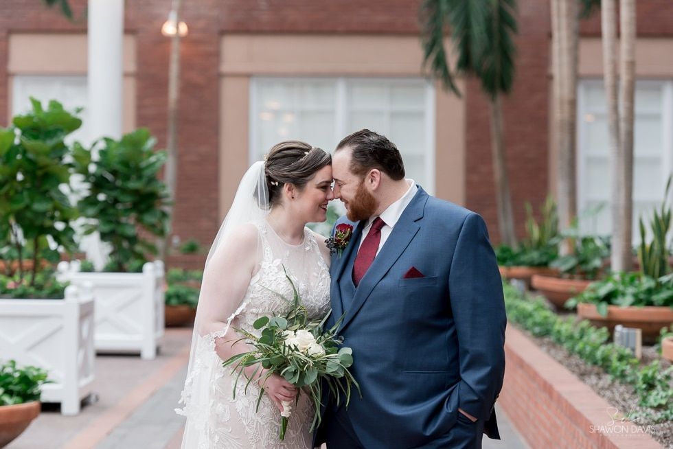 Bride and groom embracing outdoors, with bride holding a bouquet in a brick courtyard