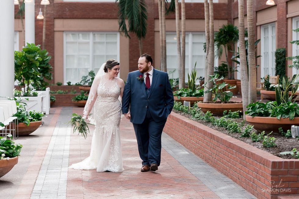 Bride and groom walking through a courtyard garden in wedding attire