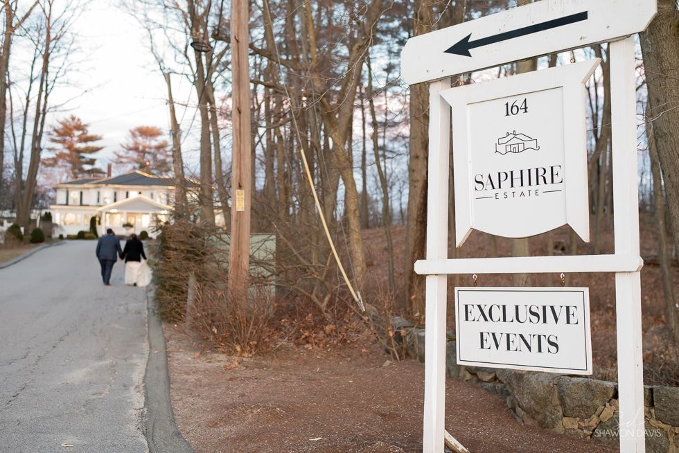 Sign for Sapphire and exclusive events beside a wooded path with two people walking toward a building