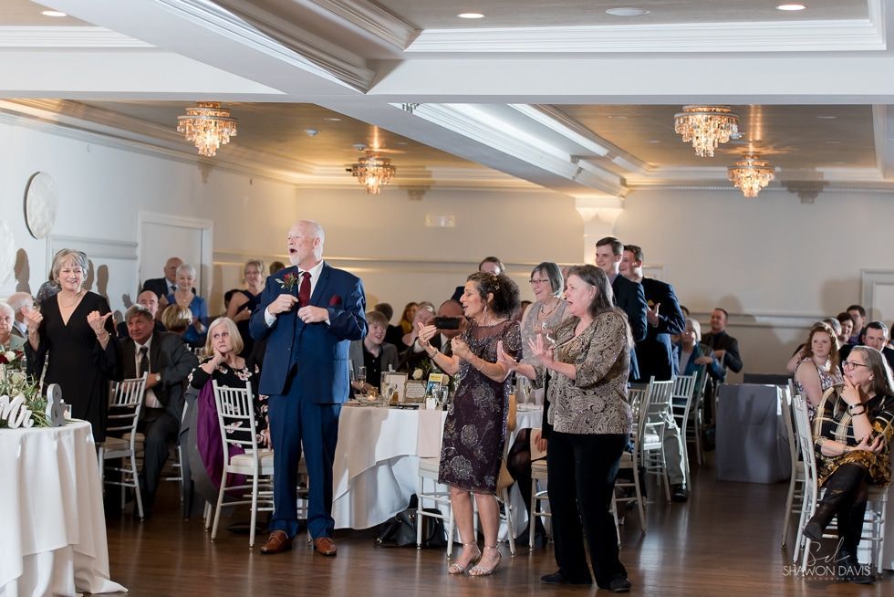 Guests standing and applauding in a banquet hall at a formal event