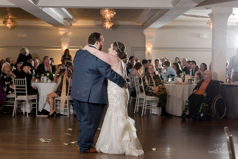 Bride and groom dancing at a wedding reception in a decorated ballroom