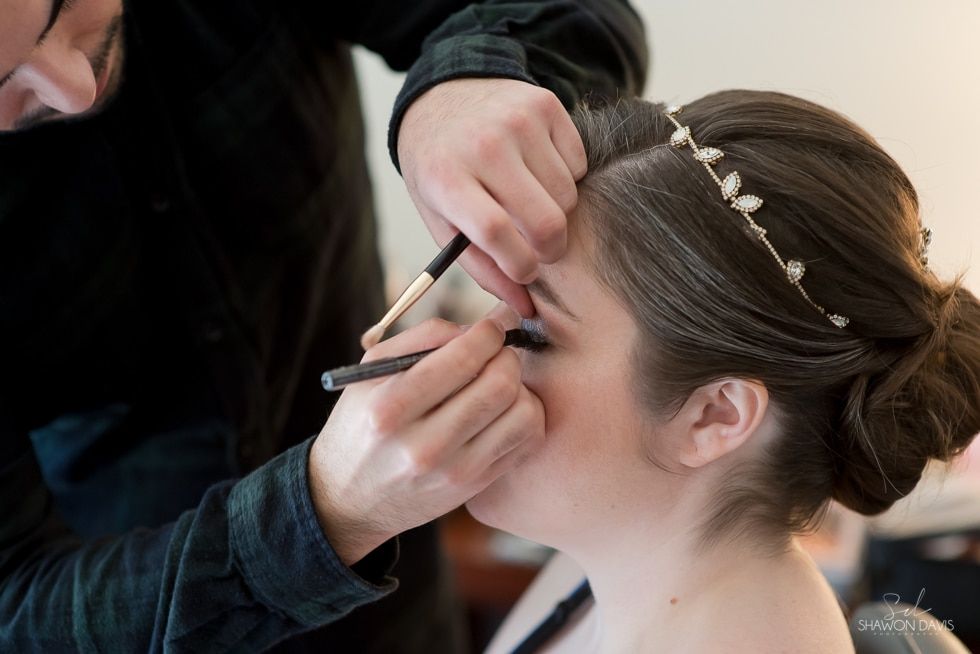 Makeup artist applying eye makeup to a woman in a close-up salon setting