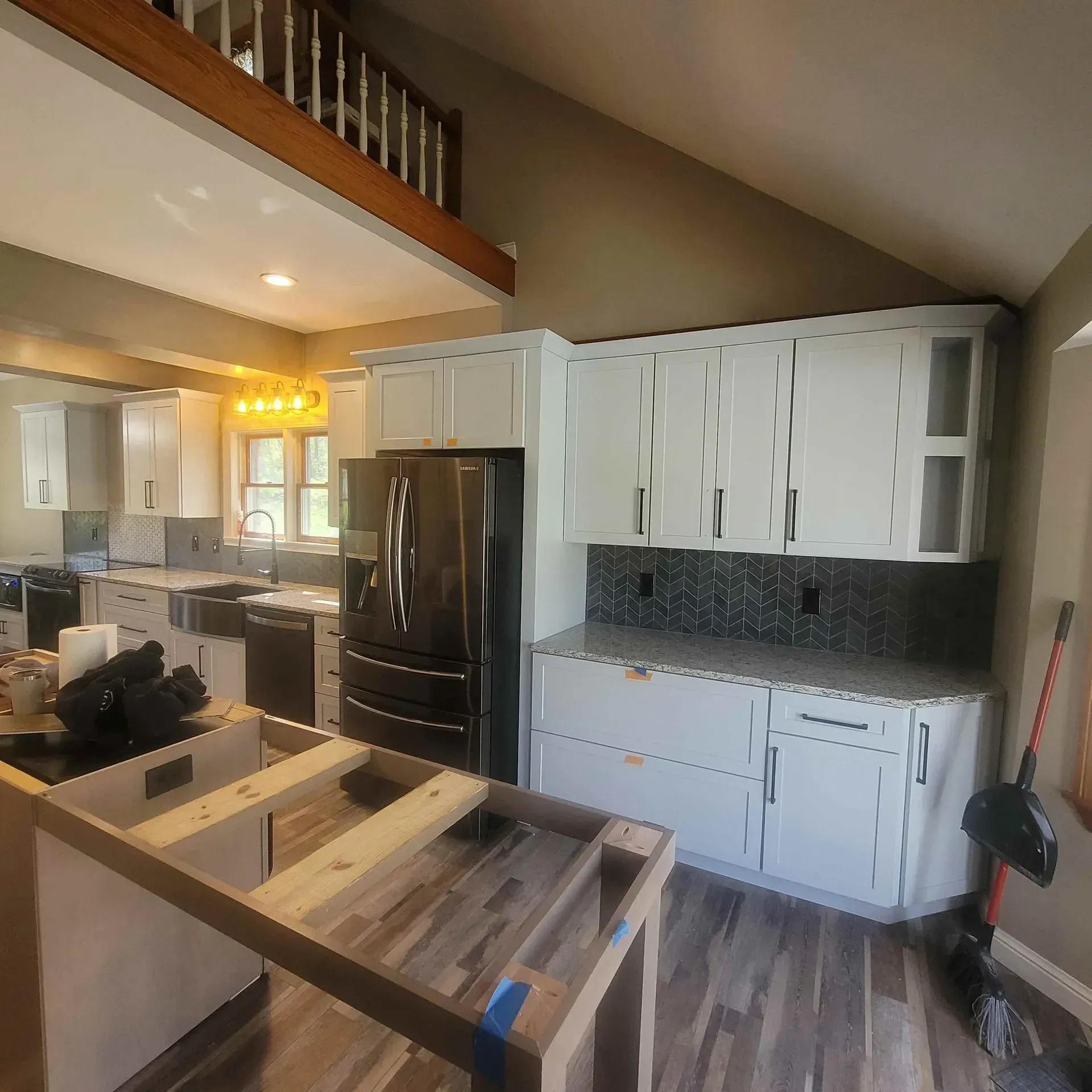 A kitchen with white cabinets and a black refrigerator