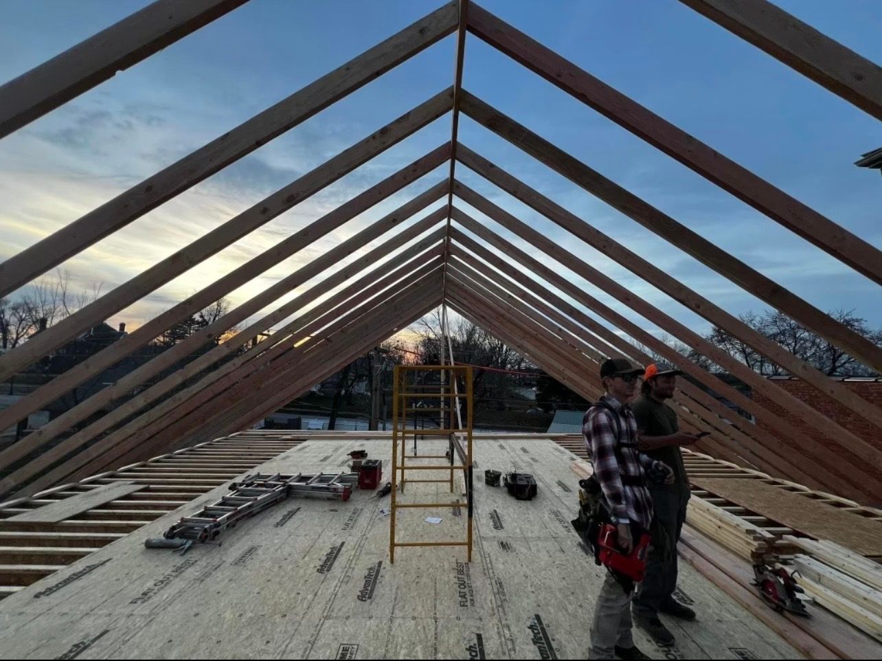 Two men are standing in the attic of a house under construction.