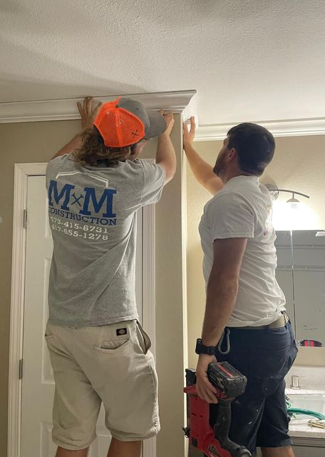 Two men are working on a ceiling in a bathroom.
