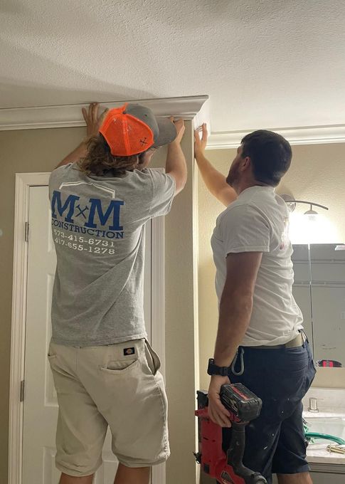 Two men are working on a ceiling in a bathroom.