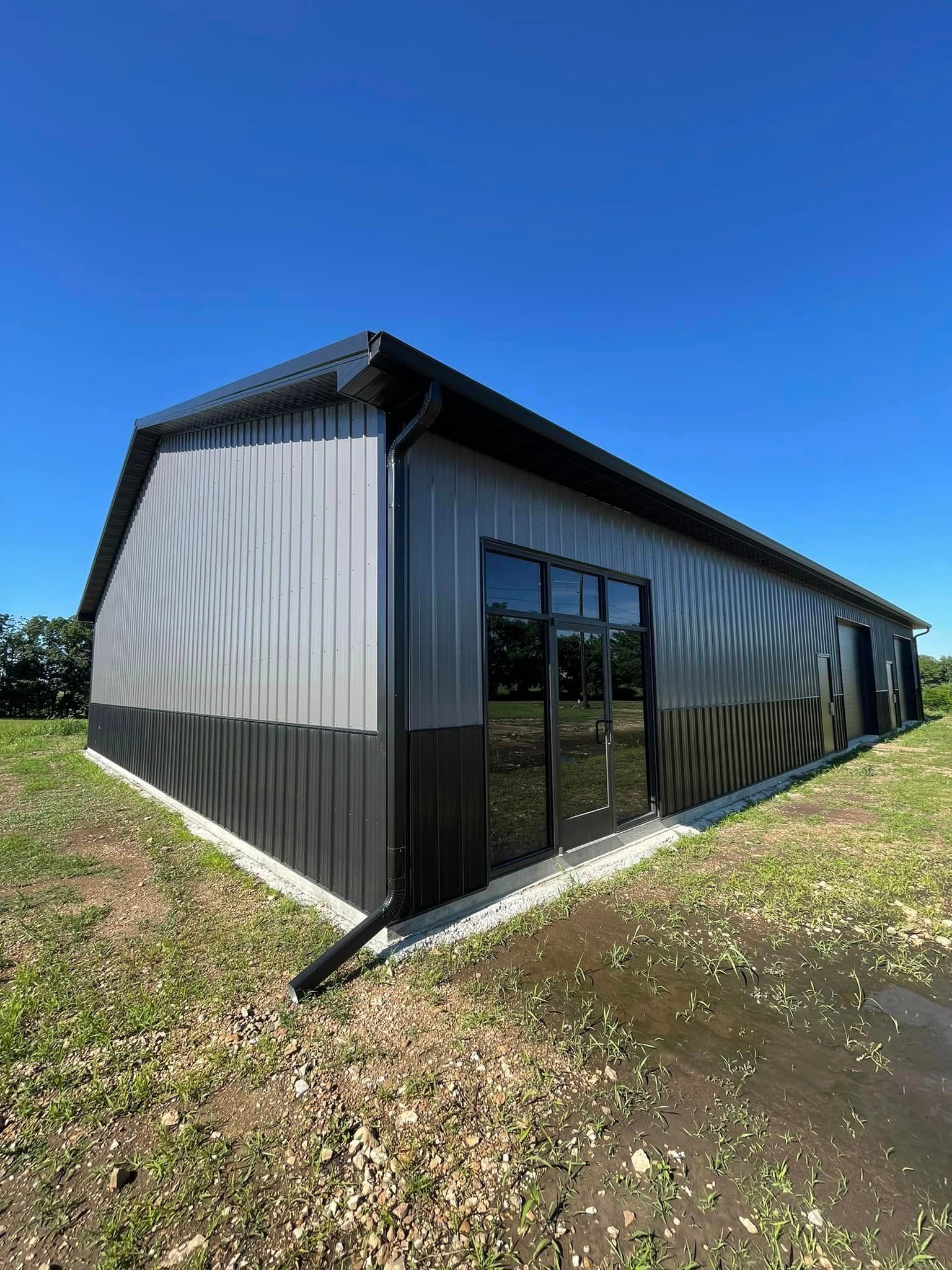 A large metal building is sitting in the middle of a grassy field.