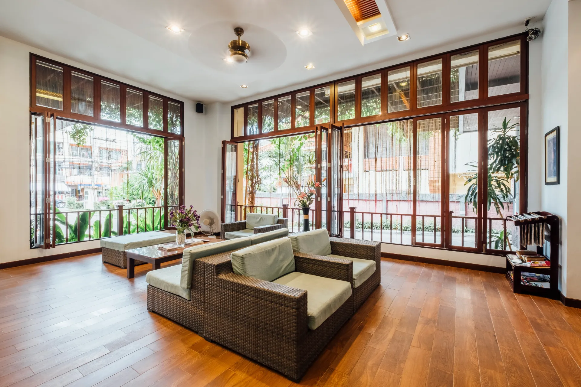 Bright living room with large windows, wooden floors, and wicker sofas in natural light