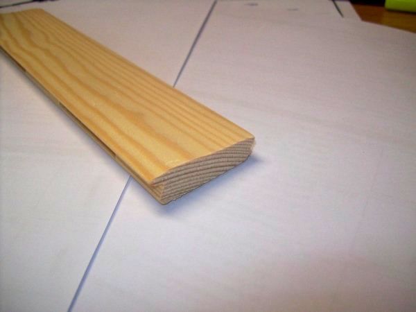 Modanatura in legno con bordo arrotondato su carta bianca.
