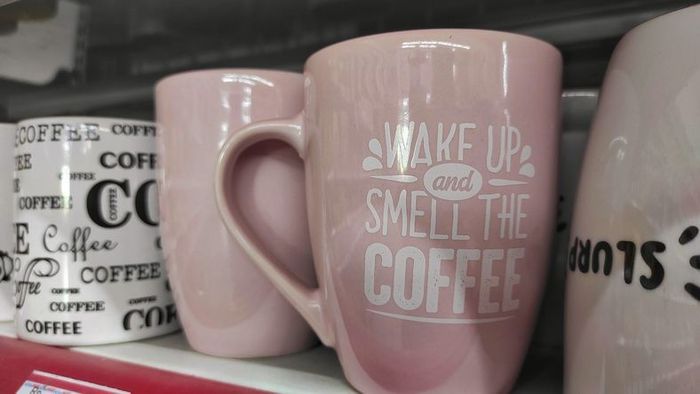 Una tazza da caffè rosa che dice svegliati e annusa il caffè