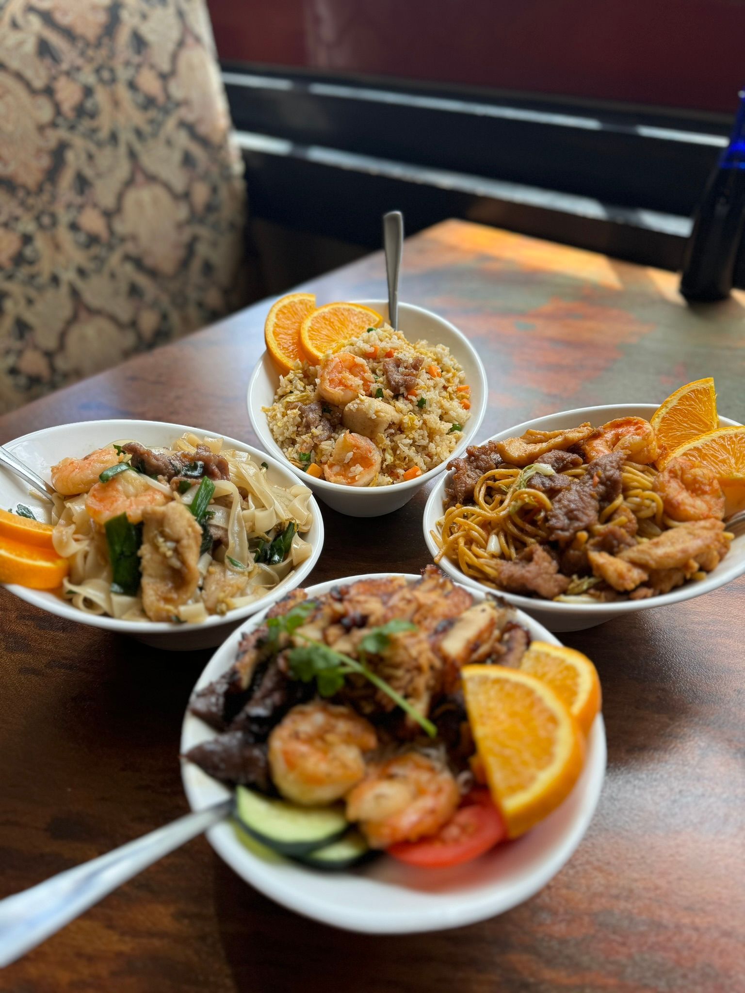 Four bowls of food are sitting on a wooden table.