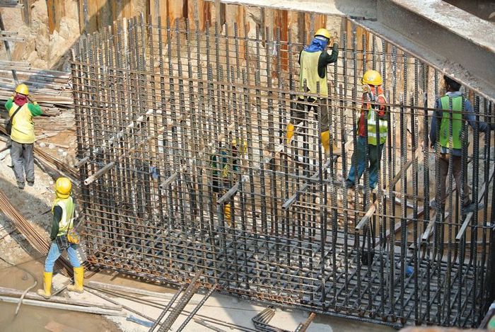 Workers placing reinforcing steel bars at a concrete construction site