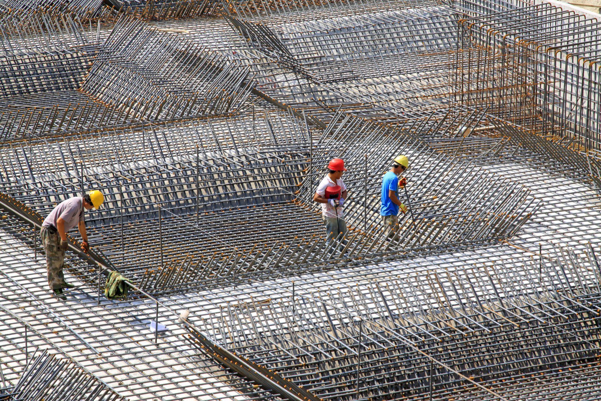 A group of construction workers are working on rebar on a building site.