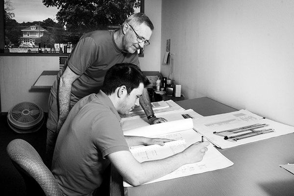 Two rebar estimators reviewing construction drawings at a desk