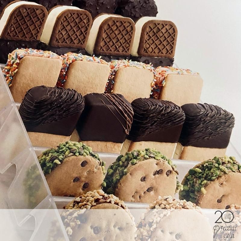 Assortimento di biscotti e pasticcini decorati, disposti in file ordinate su un vassoio.