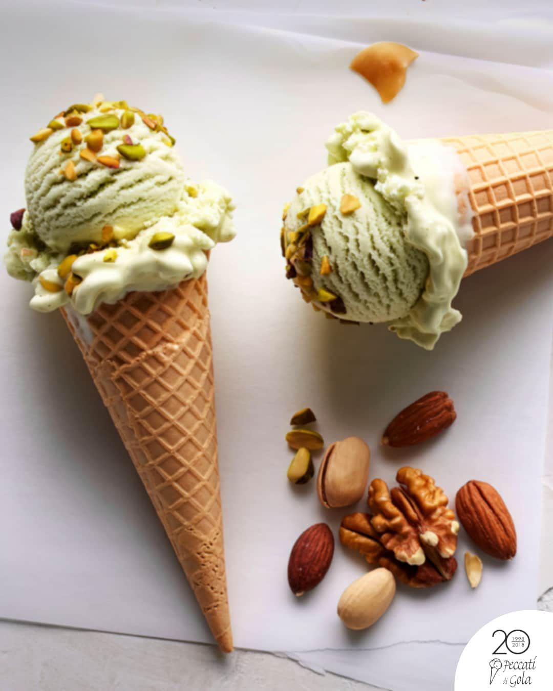 Palline di gelato al pistacchio in coni waffle con frutta secca mista su sfondo bianco