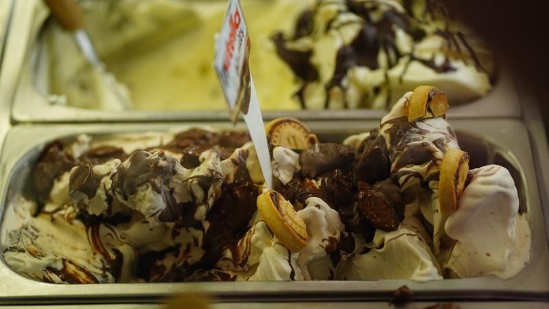 Vassoio di palline di gelato alla vaniglia ricoperte di salsa al cioccolato e noci, con cucchiaini inseriti