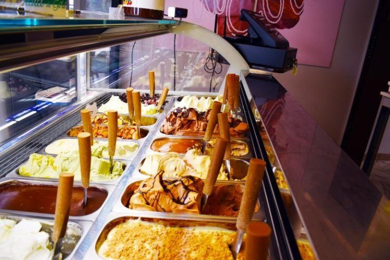 Vassoio di dessert assortiti su un bancone da buffet con fette di torta e panini sotto una luce calda