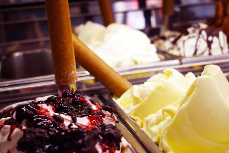 Espositore per gelati con palline di gelato al cioccolato e alla vaniglia in un banco frigo.