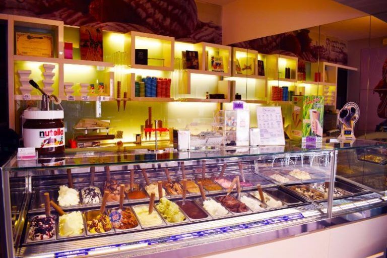 Vetrina luminosa da forno con un assortimento di pasticcini sotto calde luci gialle all'interno di un negozio