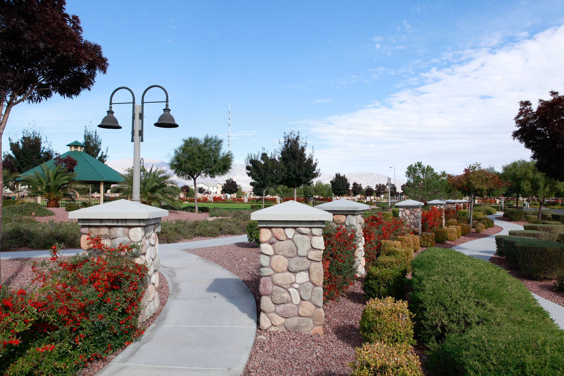 A walkway in a park with stone pillars and lights
