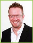 A man wearing glasses and a suit is smiling for the camera.