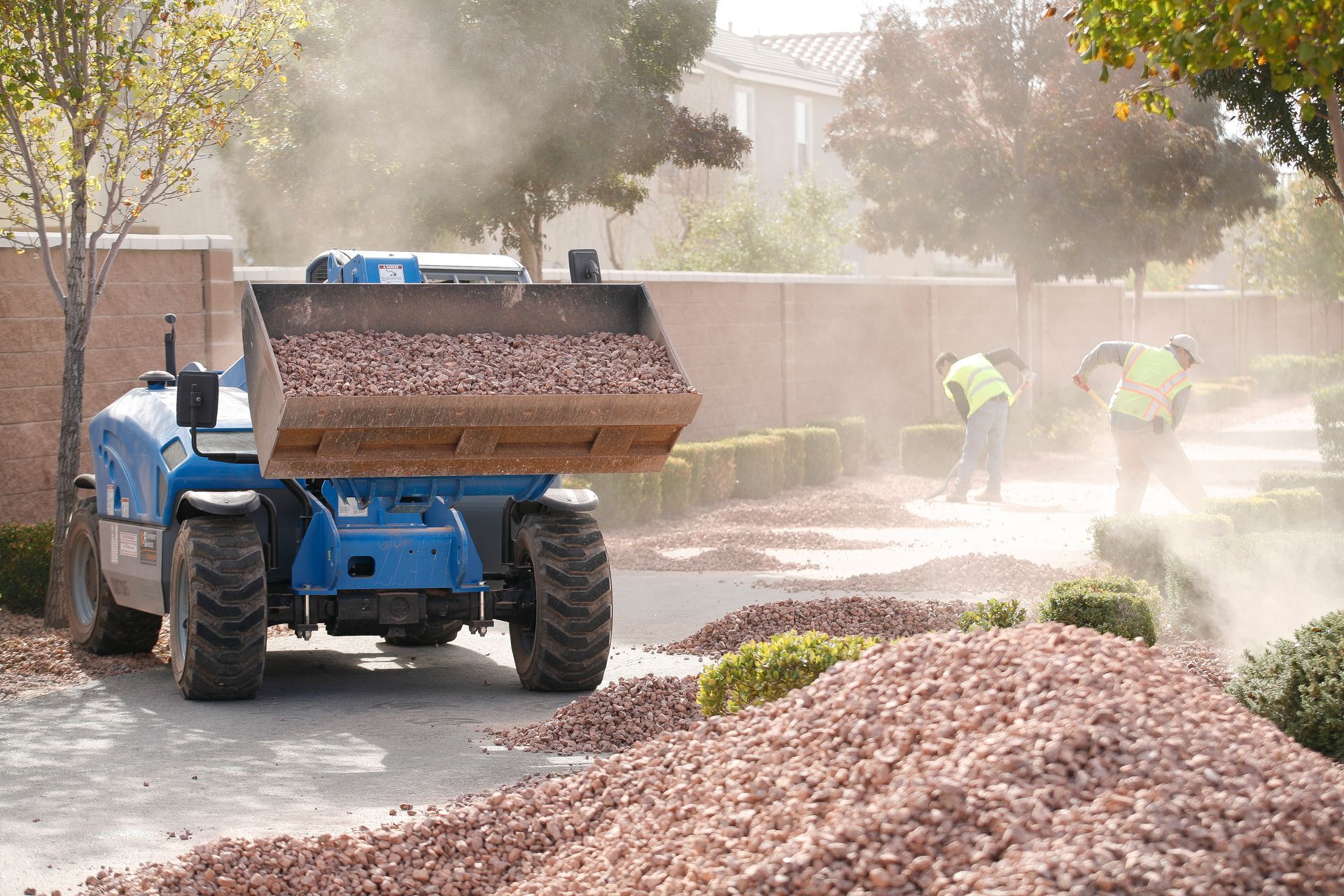 A blue tractor is loading mulch into a bucket.