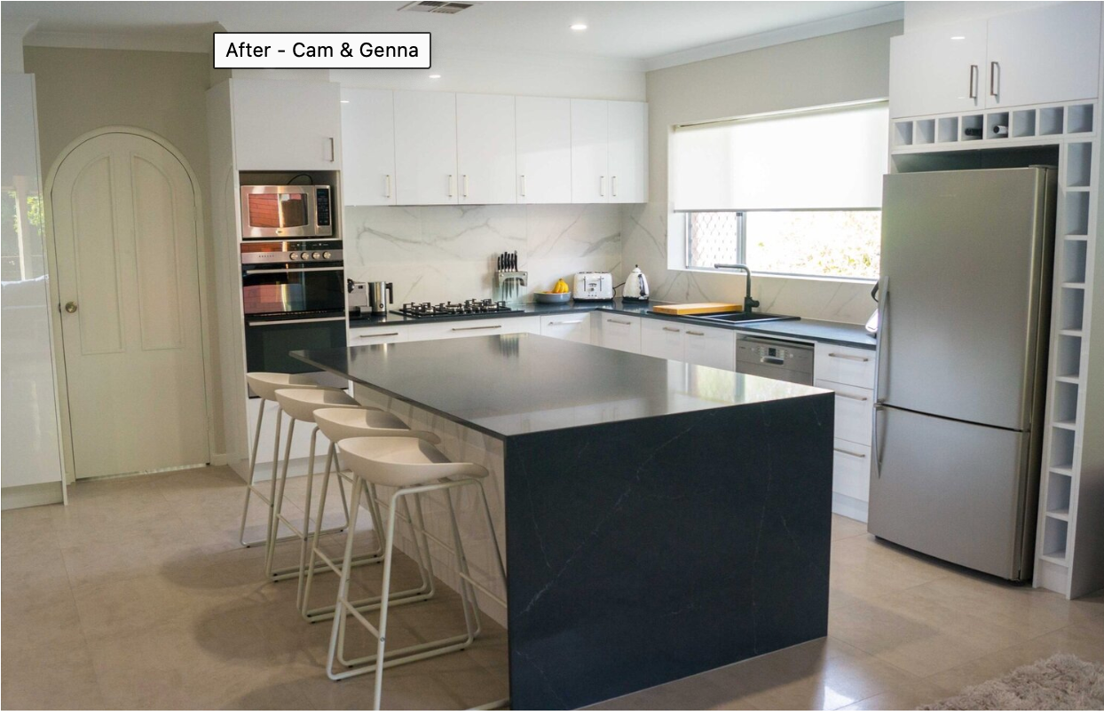 A kitchen with a large island and a stainless steel refrigerator