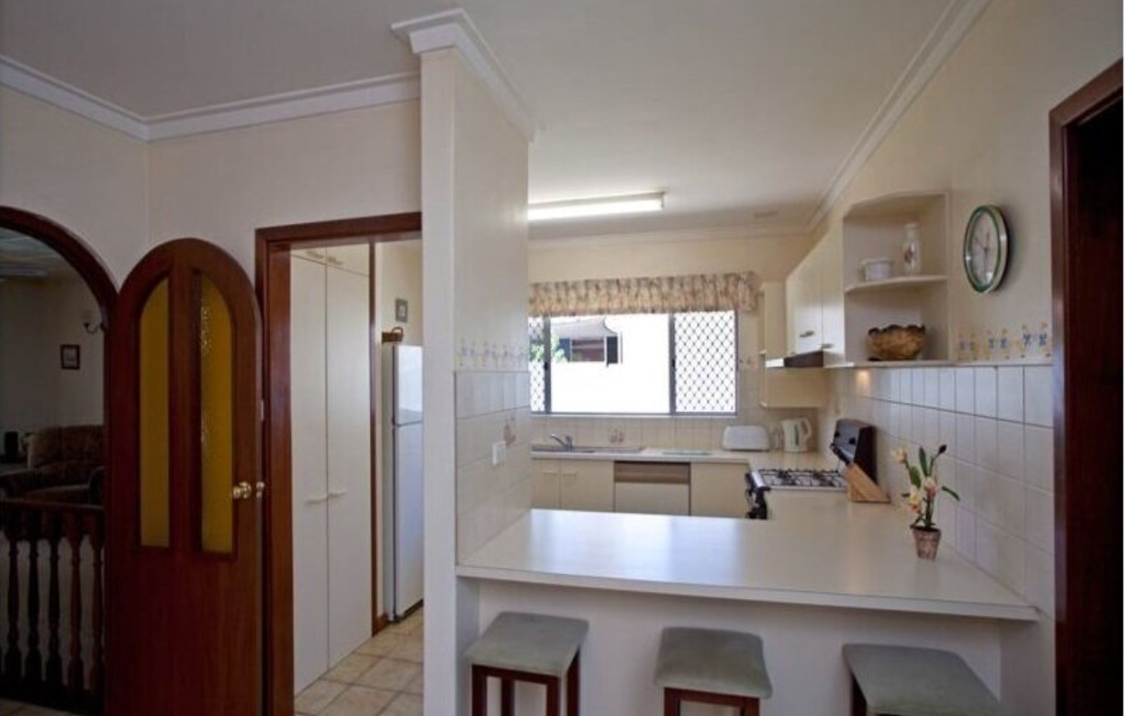 A kitchen with stools and a clock on the wall