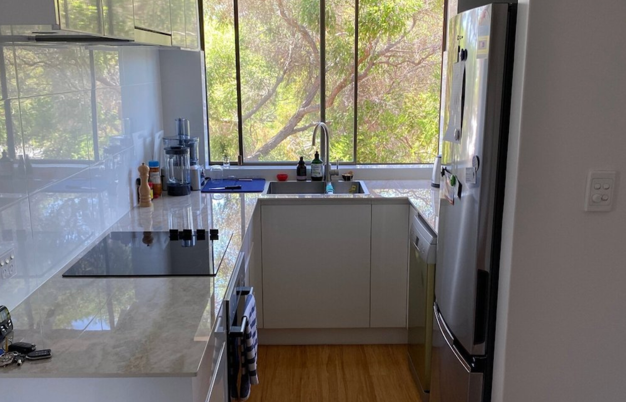 A kitchen with a stove , refrigerator , sink , and window.