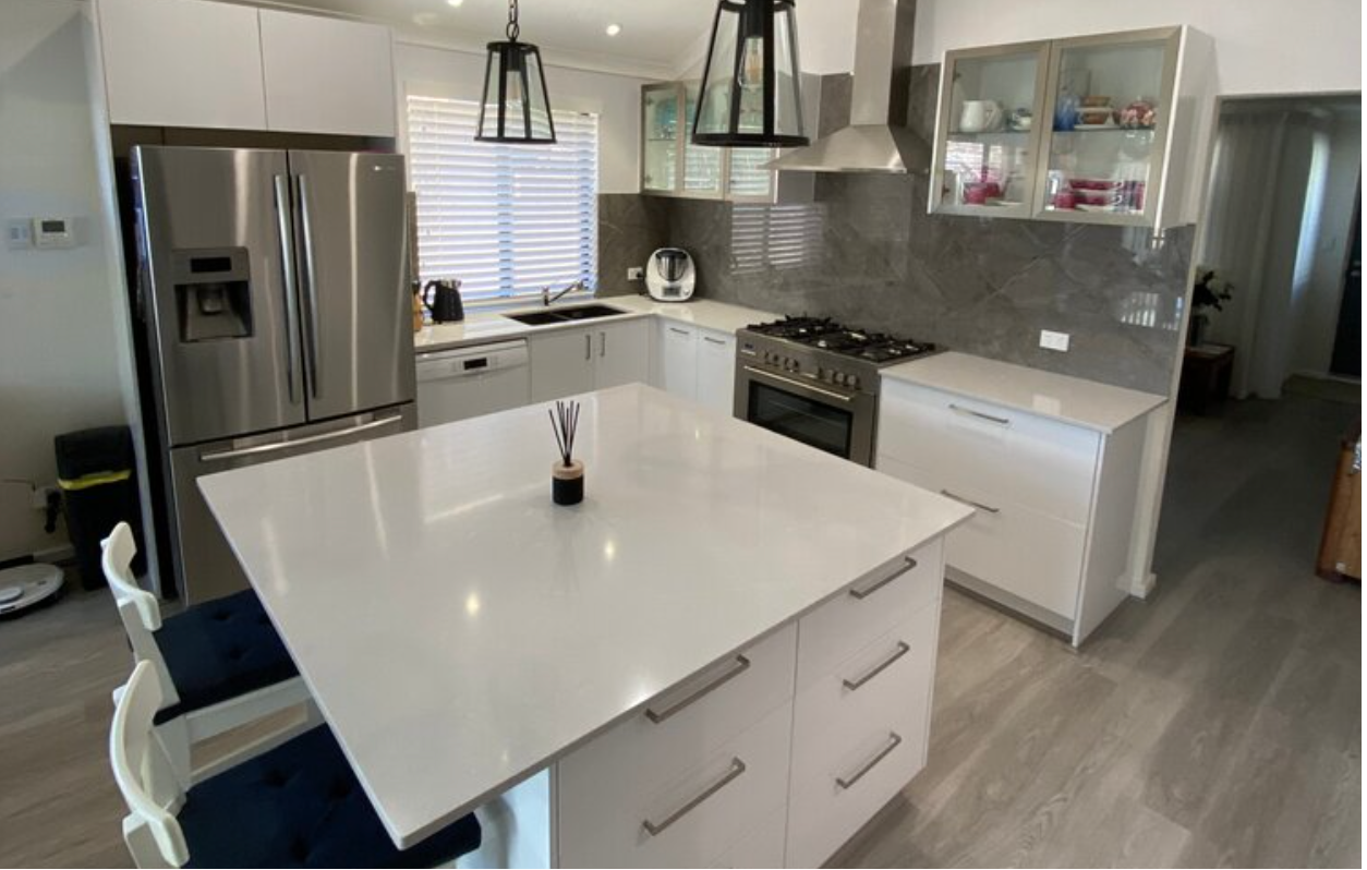 A kitchen with white cabinets and a large island in the middle.