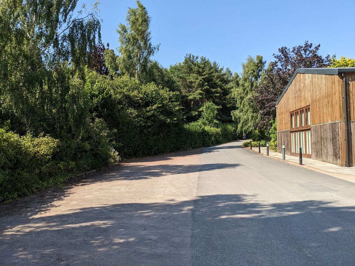 Gravelled area for parking to the right with pavement road in the centre, Grain Shed on the left