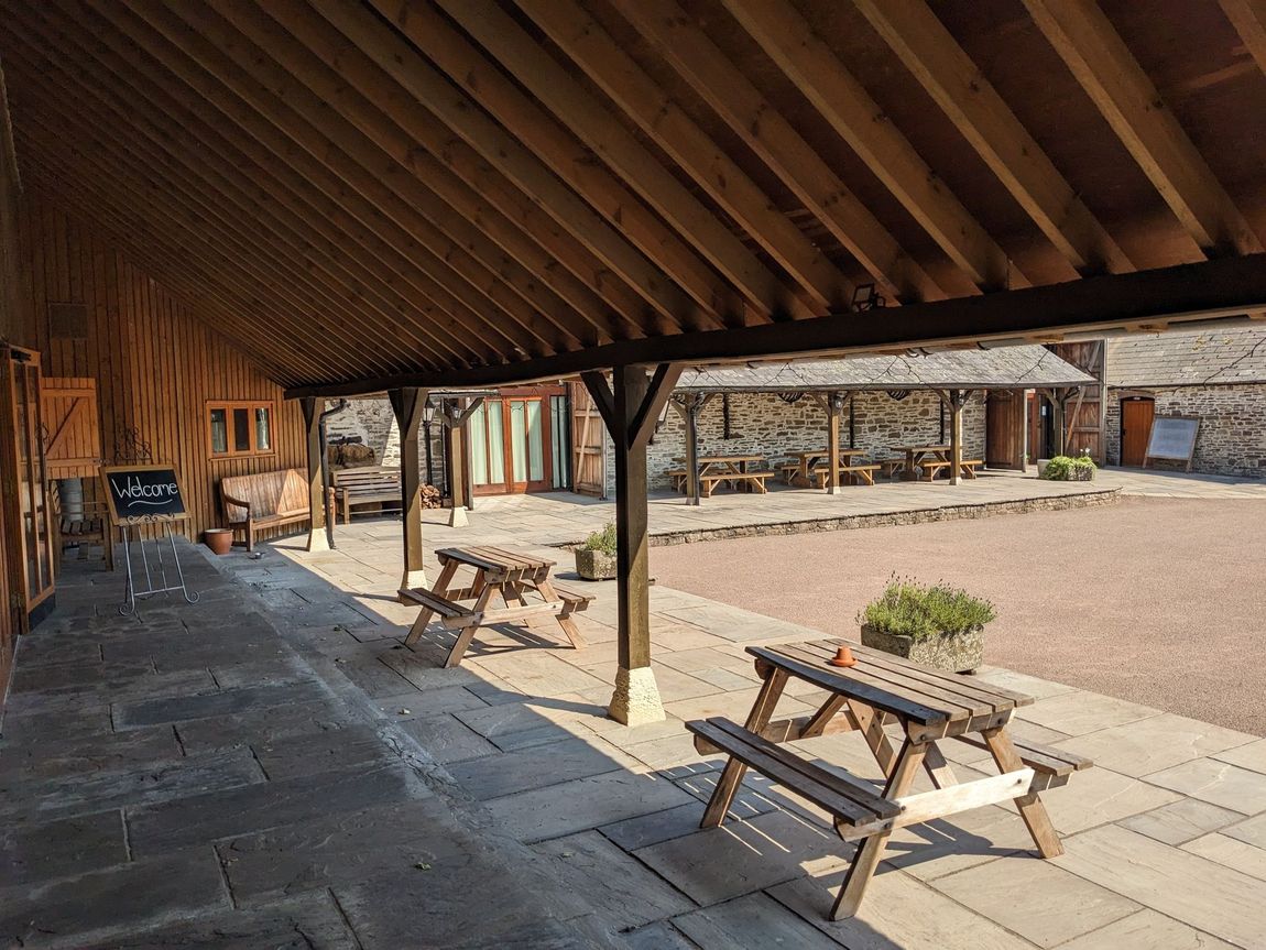 Picnic benches underneath a lean to area showing the step between the floor and building