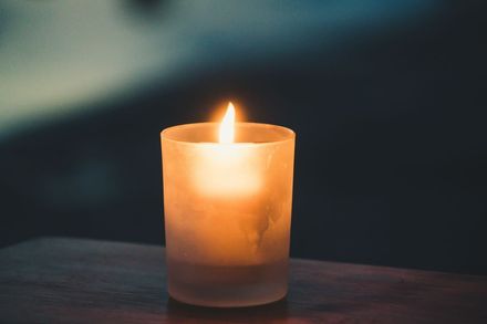 A lit candle is sitting on a wooden table next to dried berries.