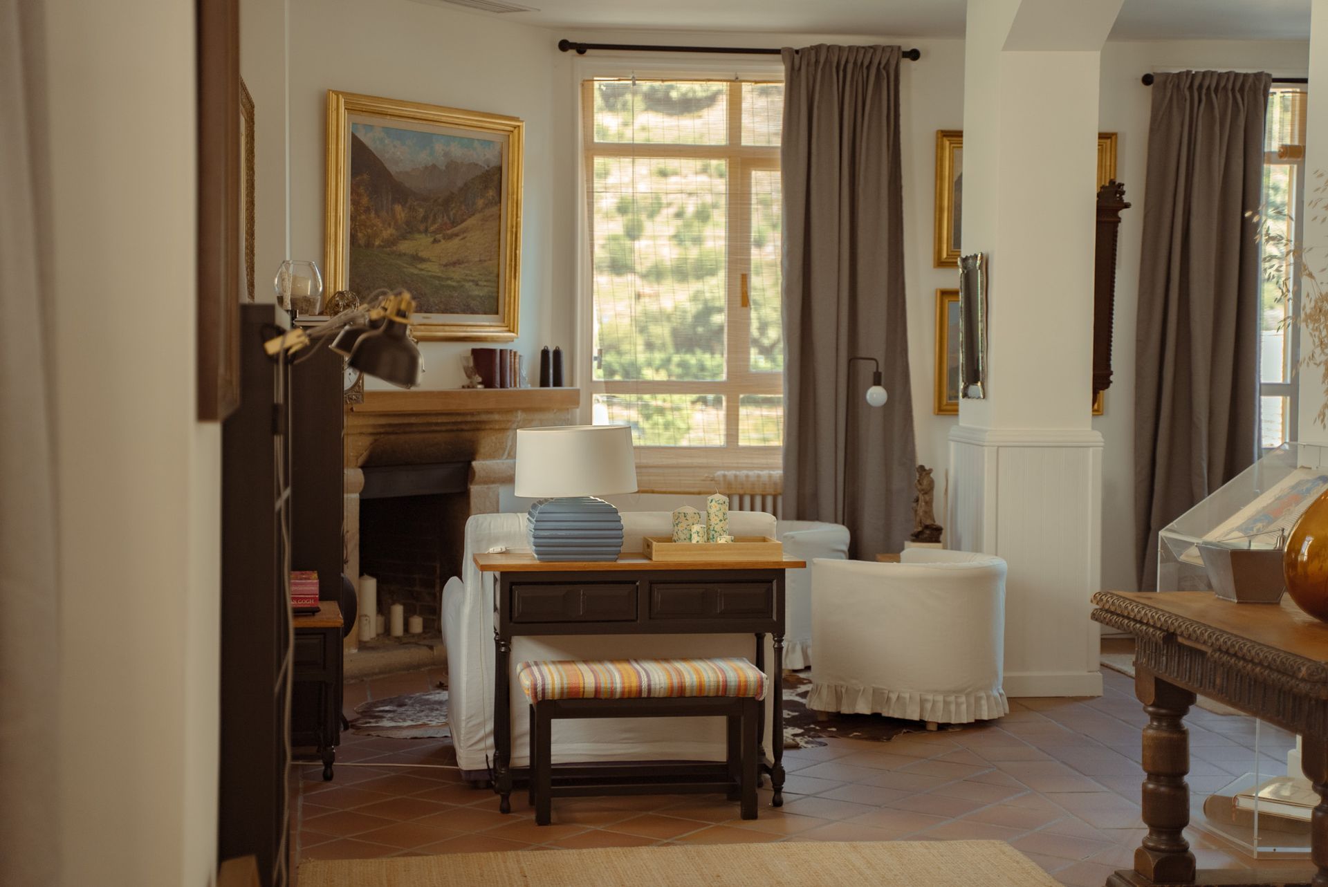 Elegante sala de estar con chimenea, ventana y libros apilados sobre una mesa.