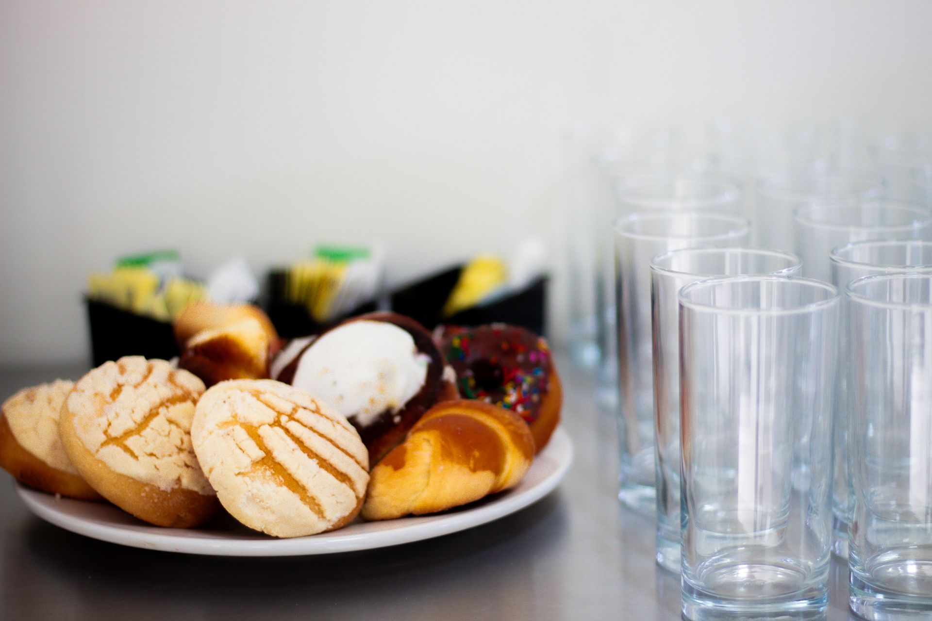 Un plato de pasteles y vasos sobre una mesa.