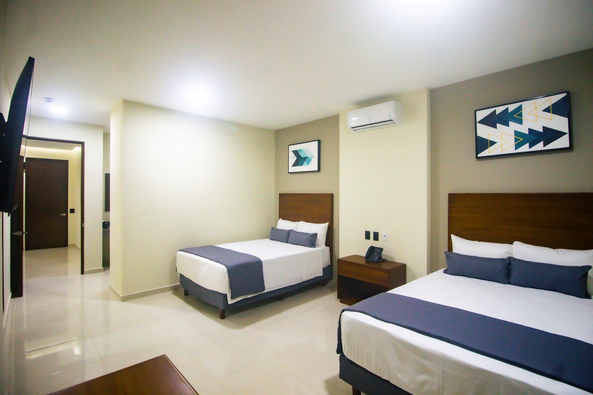 Una habitación de hotel con dos camas y un televisor de pantalla plana.