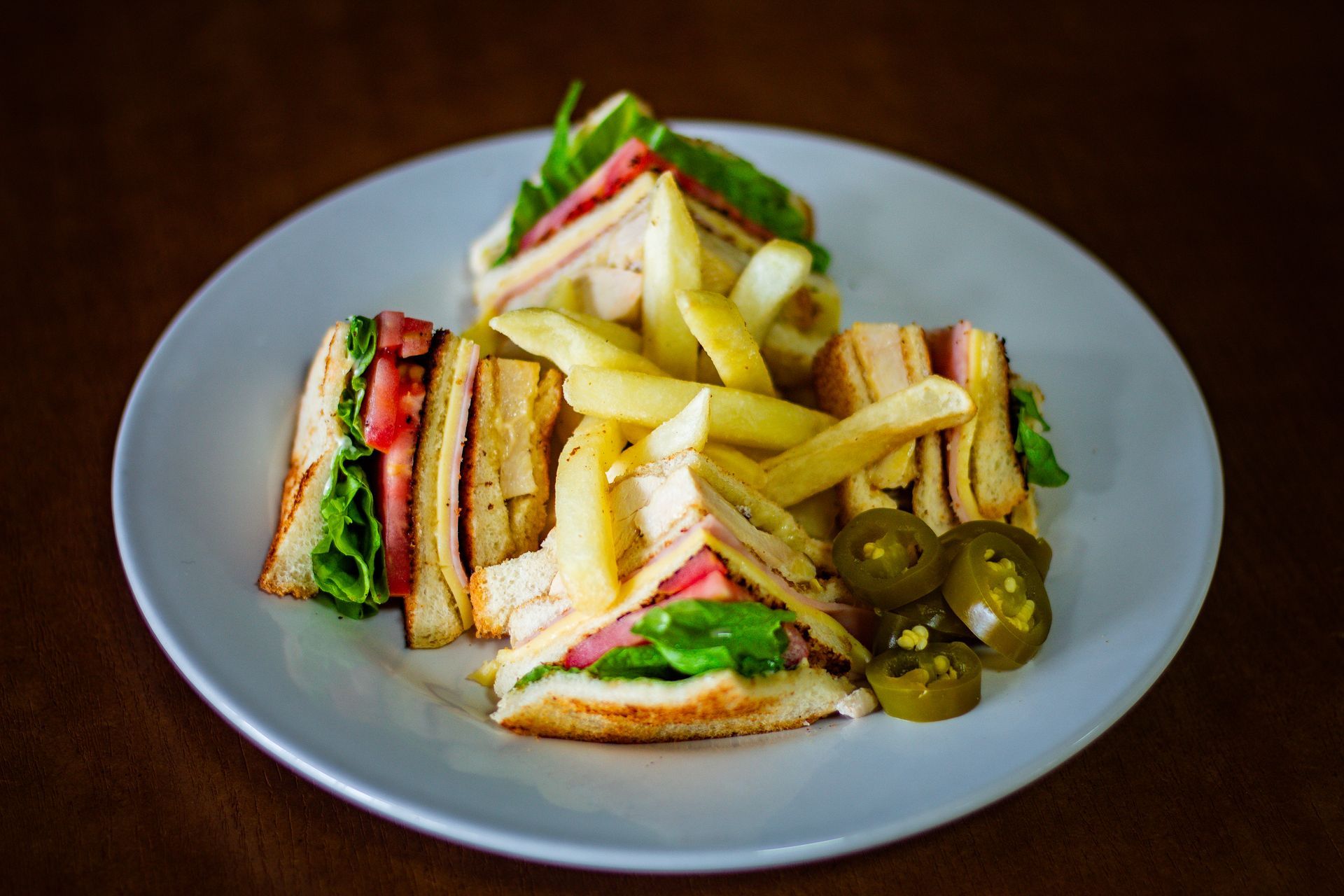 Un plato blanco cubierto con un sándwich club y papas fritas.