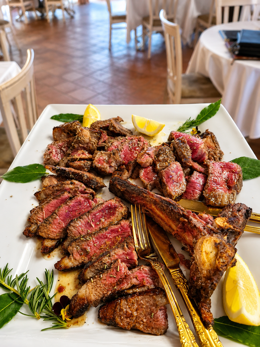 In un ristorante, fette di bistecca grigliata con limone e asparagi su un piatto bianco.