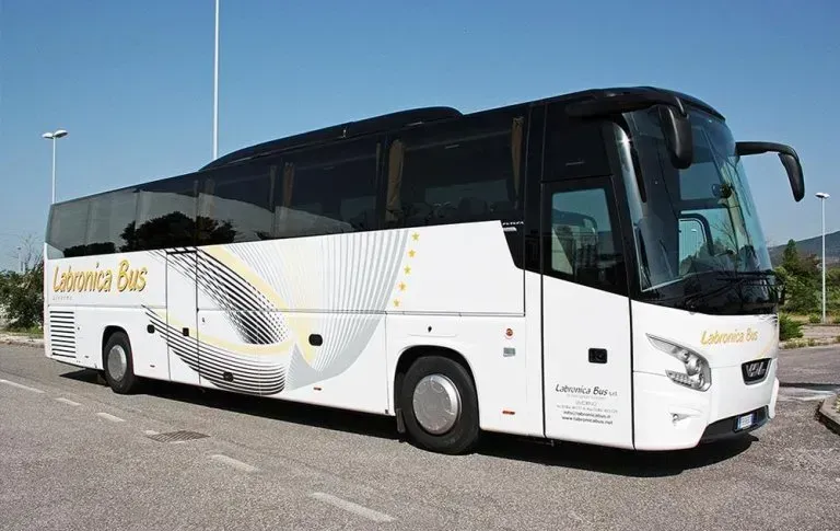 Un pullman bianco della Labronica Bus parcheggiato su una superficie asfaltata sotto un cielo azzurro e limpido.