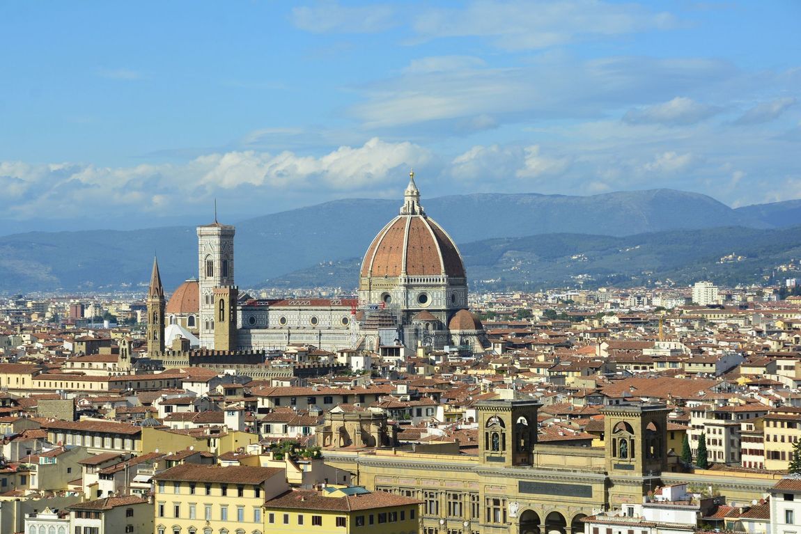 Una vista panoramica di Firenze, Italia, con l'iconica cupola in terracotta del Duomo sotto un cielo azzurro brillante.