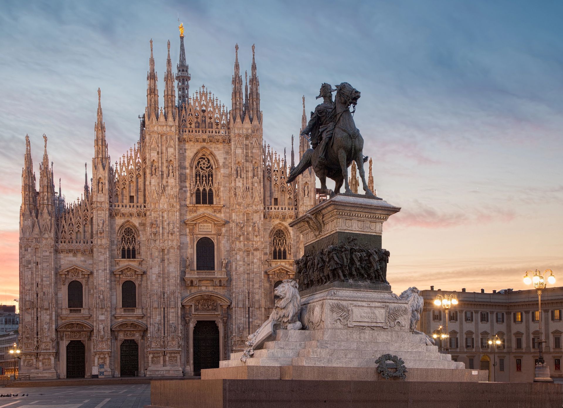 Il Duomo di Milano si staglia alle spalle della statua equestre di Vittorio Emanuele II al crepuscolo.