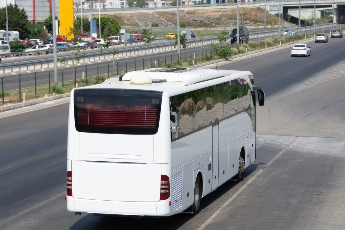 Un autobus turistico bianco che percorre un'autostrada asfaltata durante il giorno.