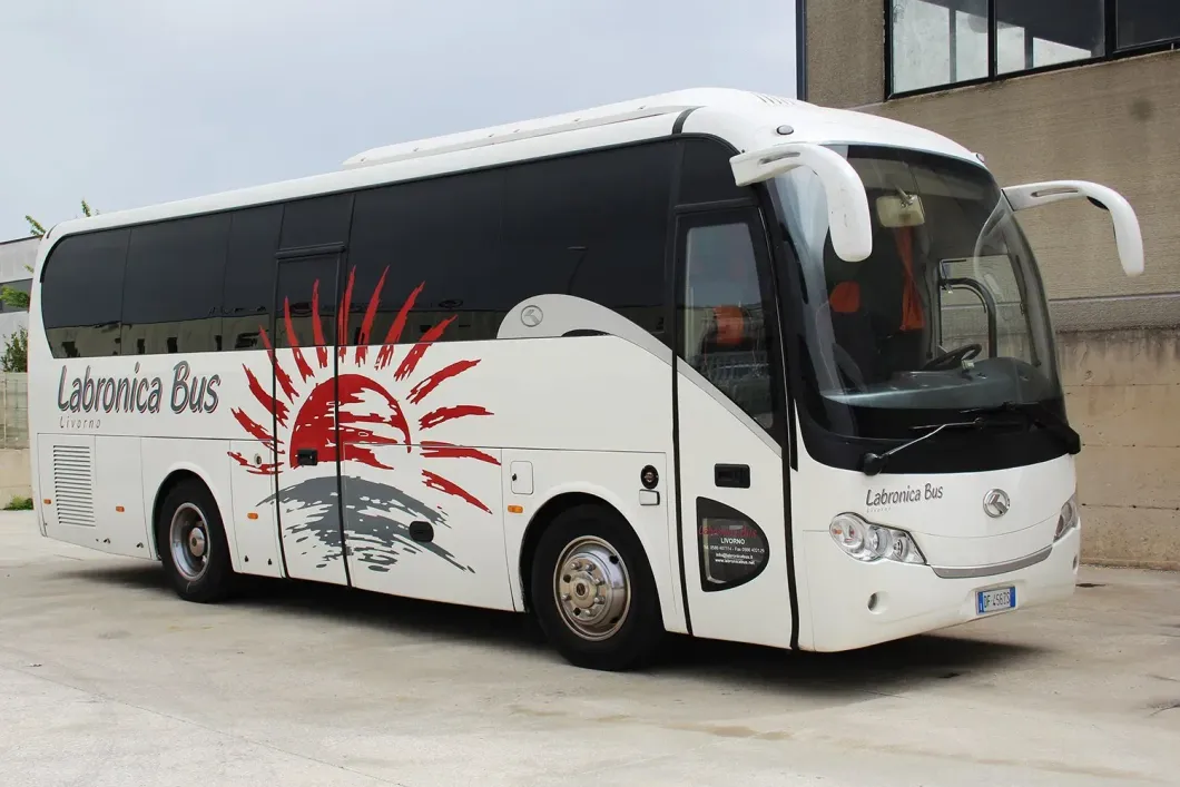 Autobus turistico bianco Labronica Bus parcheggiato sul cemento, con il logo di un'alba rossa sul lato.