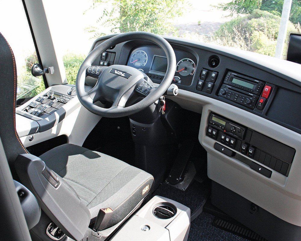 Posto di guida e cruscotto di un moderno autobus turistico, con volante, quadro strumenti e pulsanti di controllo.